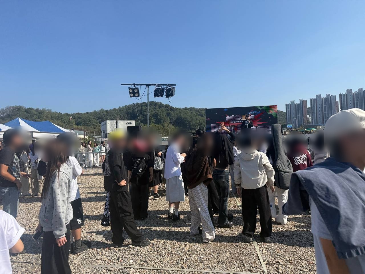 플레이 스테이지 LED 화면 앞 자갈 바닥에 청소년 관객들이 모여 서 있다. 인물 얼굴은 흐리게 처리했다