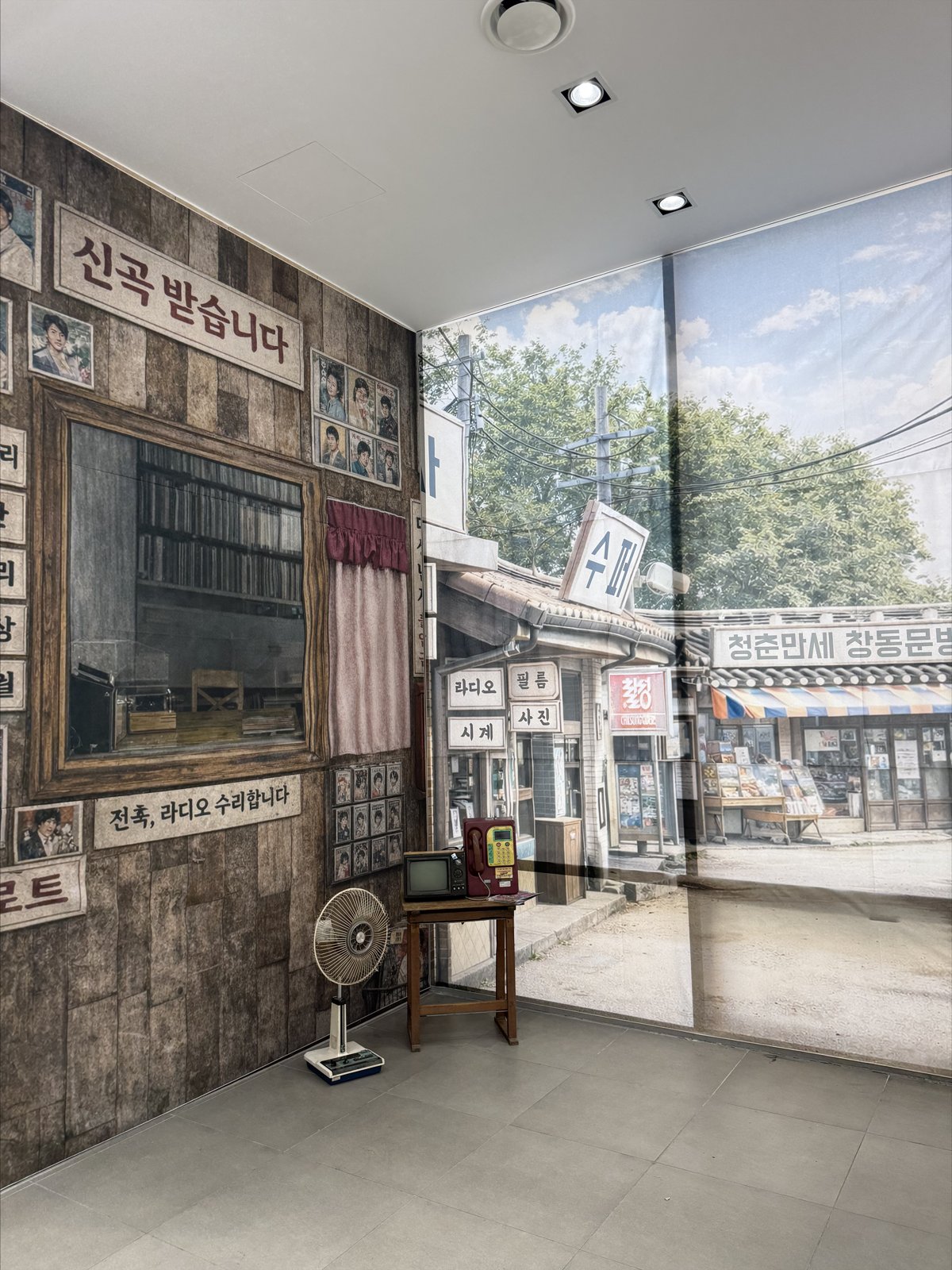 옛날 간판과 골목 풍경 사진을 붙인 전시 벽 앞에 선풍기와 생활 소품이 놓여 있다